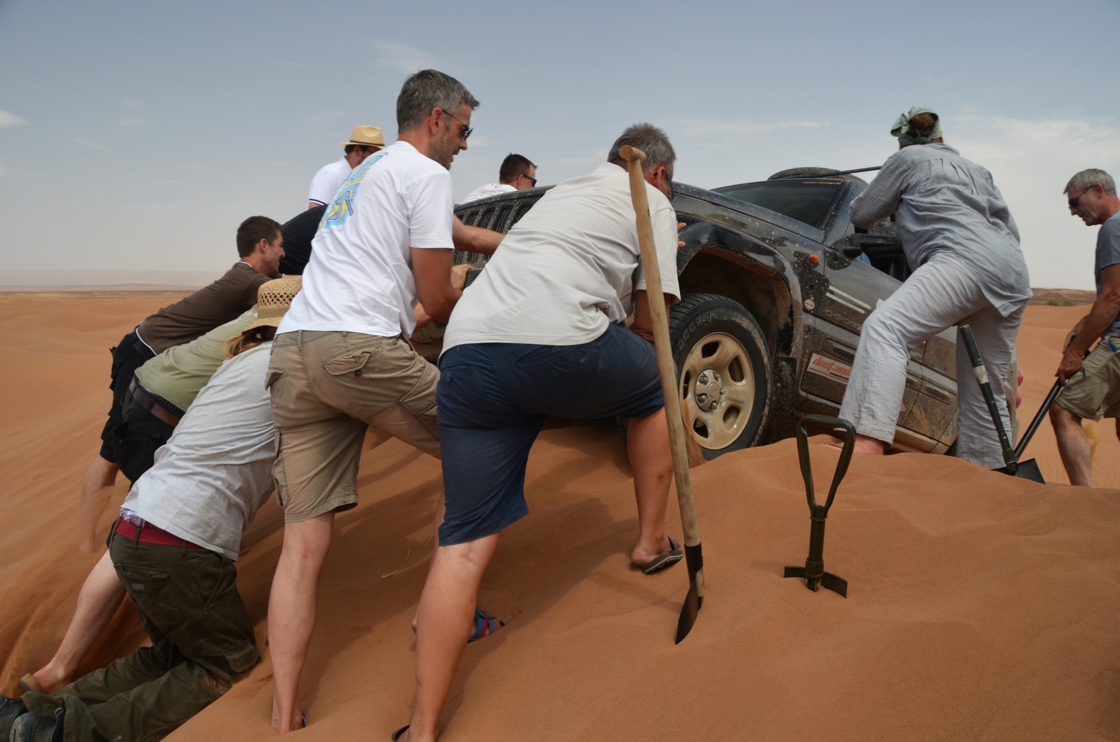 Teilnehmer von Maroc-Voyage schieben einen Jeep im Erg Chegaga